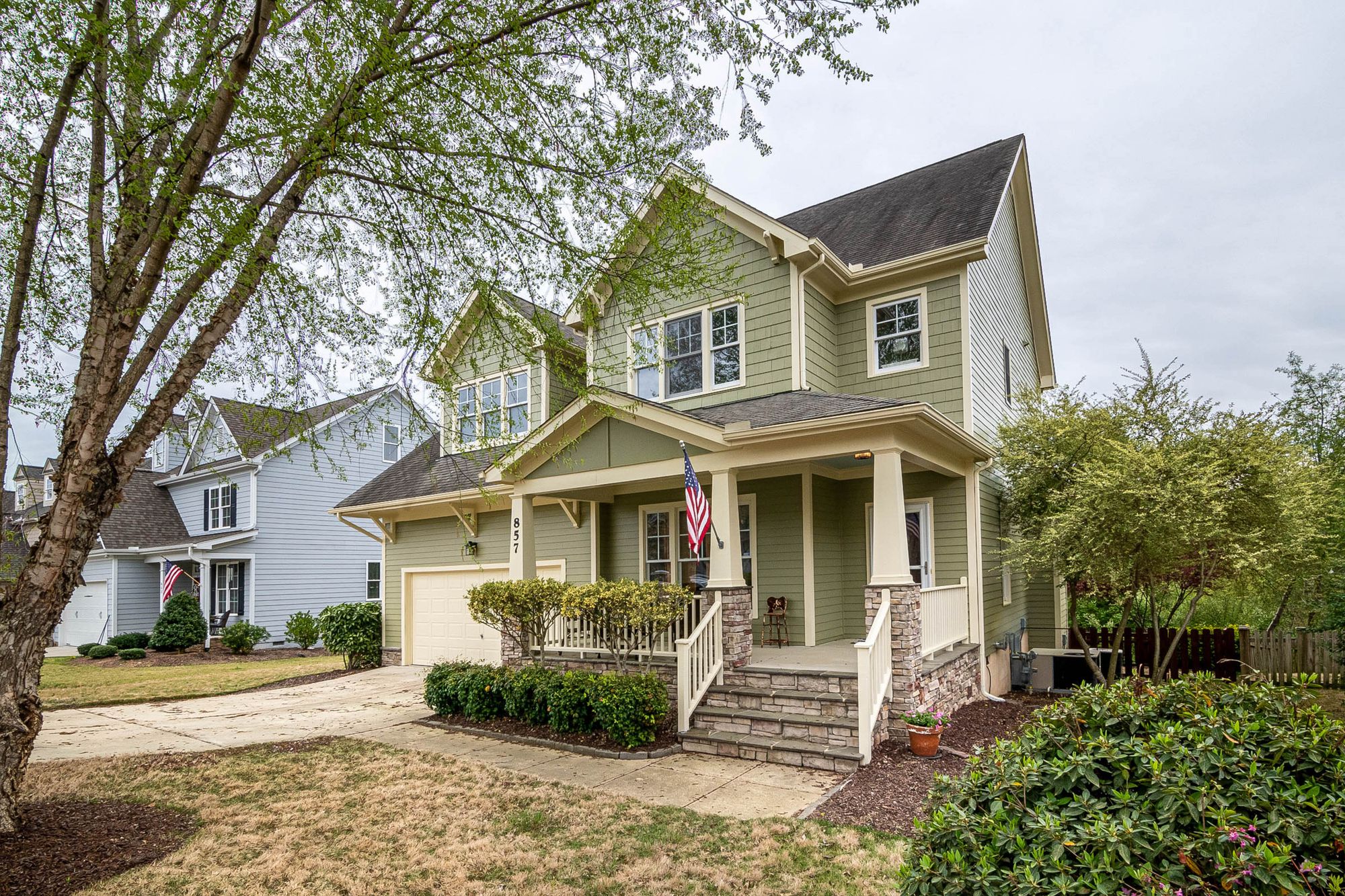 A craftsman-style family home with a covered front porch and an American flag